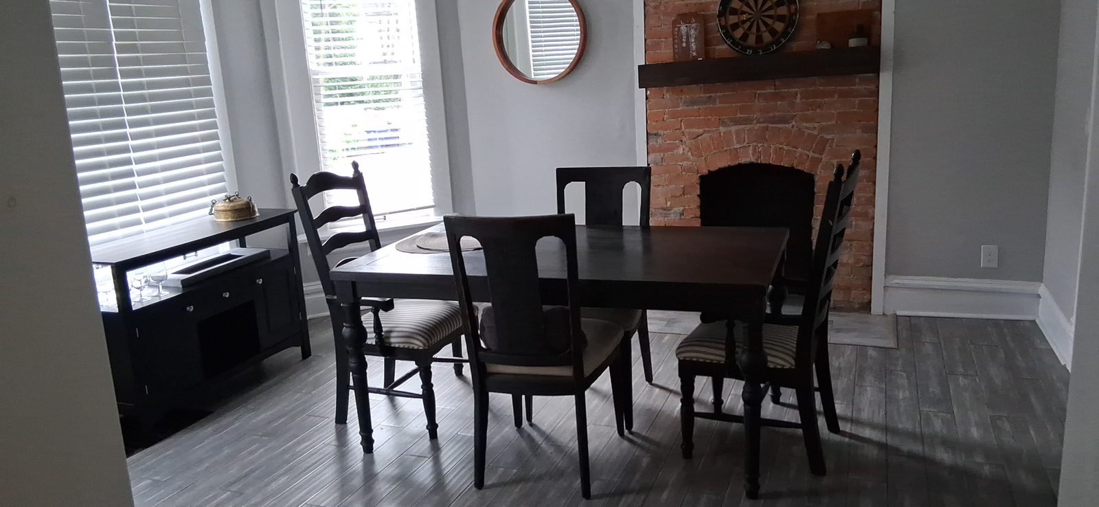 Dining area reset between guests Dining area with dark wood table and chairs beside a brick fireplace in a Columbus rental