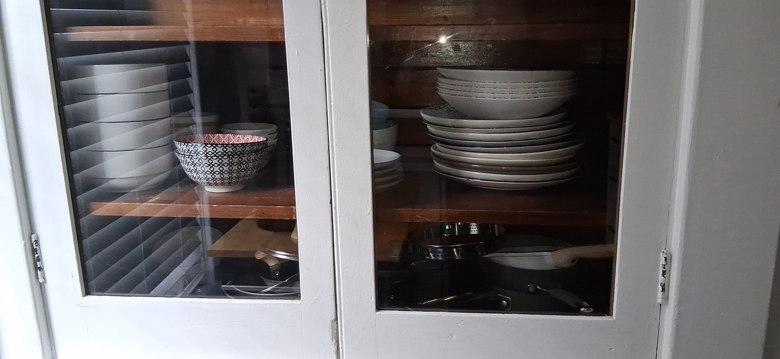 Dishware cabinet in a short-term rental Glass-front cabinet stocked with clean plates, bowls and mugs in a short-term rental