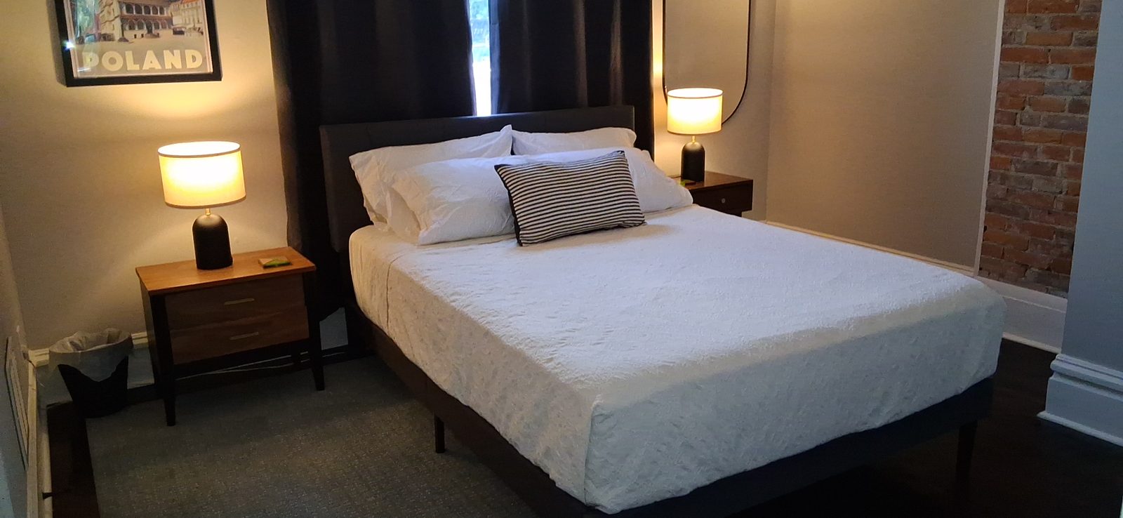 Guest-ready bedroom after a turnover clean Short-term rental bedroom with a crisply made white bed, matching lamps and framed art, ready for check-in