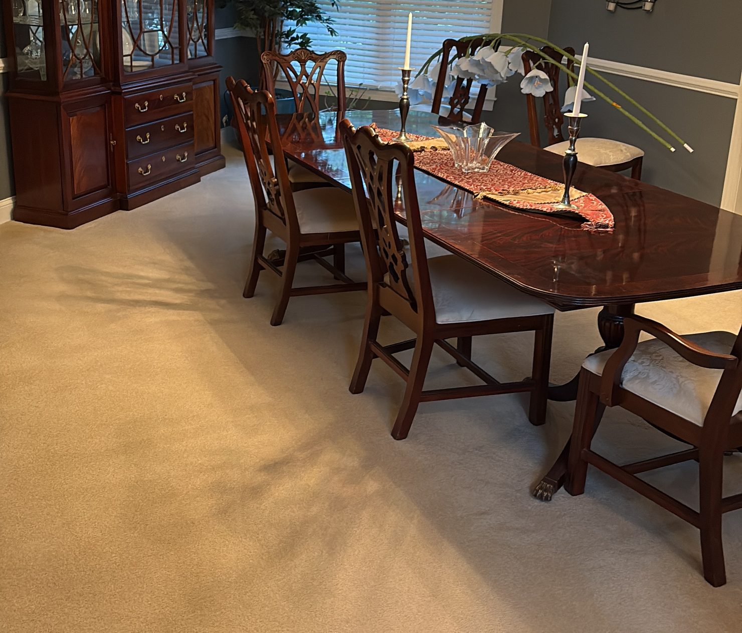 Dining room with a polished table, chairs and vacuumed carpet after a cleaning visit
