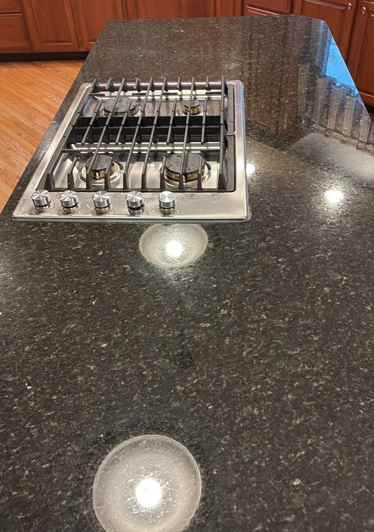 Polished counter and cooktop detail Polished granite countertop and gas cooktop after detailed kitchen cleaning