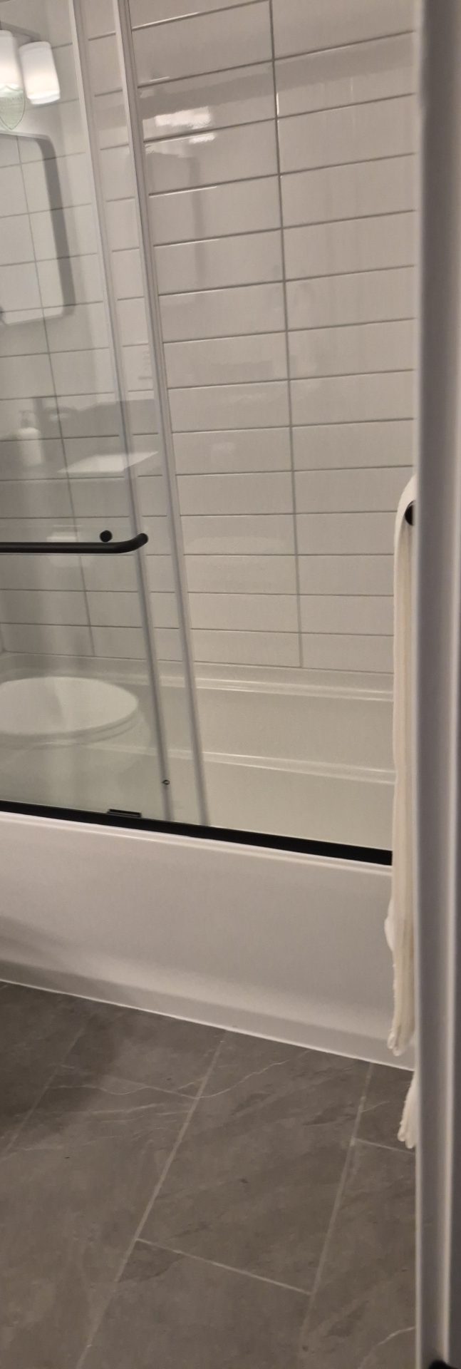 Bathroom prepared for occupancy Bathtub with a glass shower screen and tiled floor in a cleaned bathroom