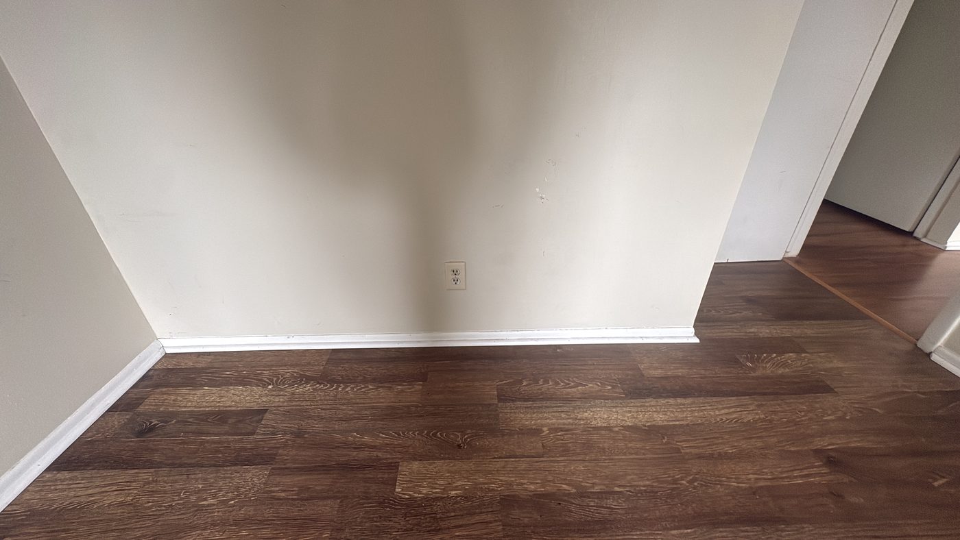 Accessible floors in an empty home Corner of an empty room with cleaned floor and white baseboards