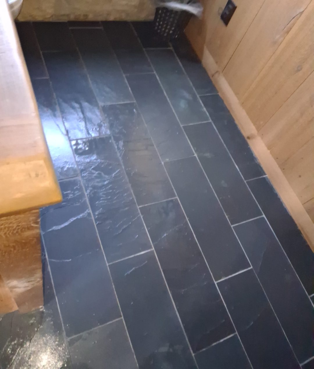 Slate floor after final detail cleaning Slate tile floor cleaned to a sheen beside natural wood paneling